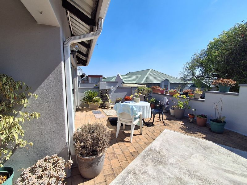 A sunny, paved outdoor patio area featuring a low parapet wall and direct access to the main dwelling.