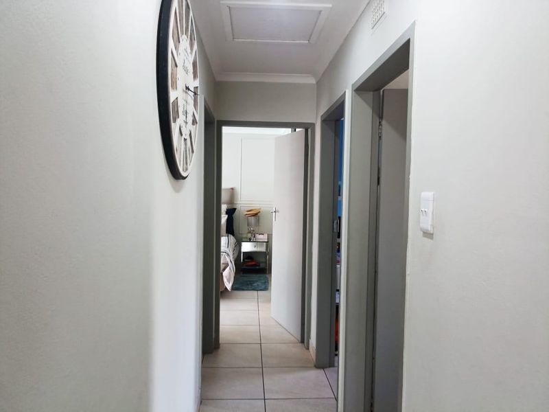 A clean, neutral-toned hallway featuring tiled flooring and access to multiple rooms, providing a functional transition space within the home.