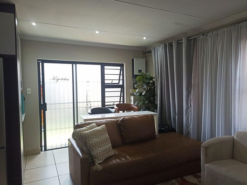 A well-lit living room featuring tiled flooring, recessed downlights, and a sliding glass door providing access to the exterior.