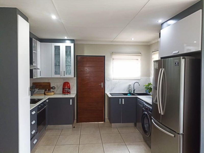 Modern kitchen featuring two-tone cabinetry, stone countertops, integrated appliances, tiled flooring, and recessed lighting in a functional layout.