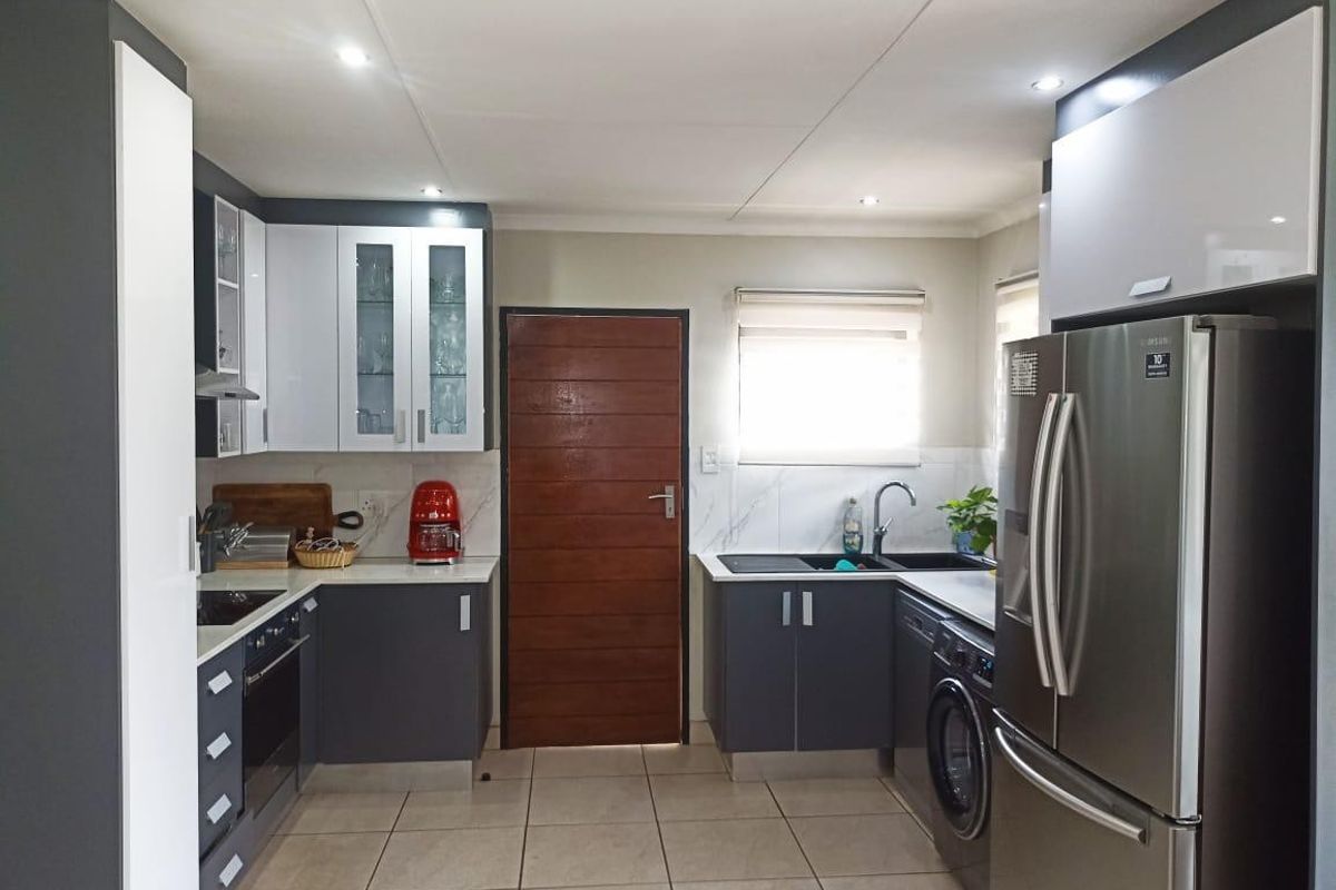 Modern kitchen featuring two-tone cabinetry, stone countertops, integrated appliances, tiled flooring, and recessed lighting in a functional layout.