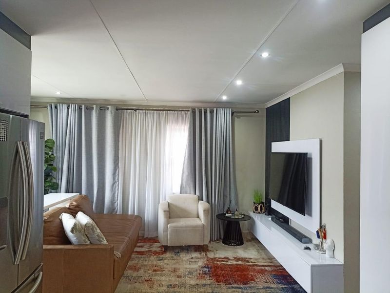 Modern open-plan living area featuring a sleek built-in media console, feature wall paneling, and recessed downlighting, creating a bright and contemporary atmosphere.