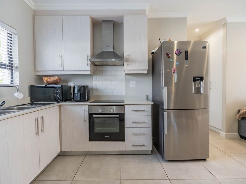 A functional kitchen featuring light wood-finish cabinetry, a subway tile backsplash, stainless steel appliances, and tiled flooring.