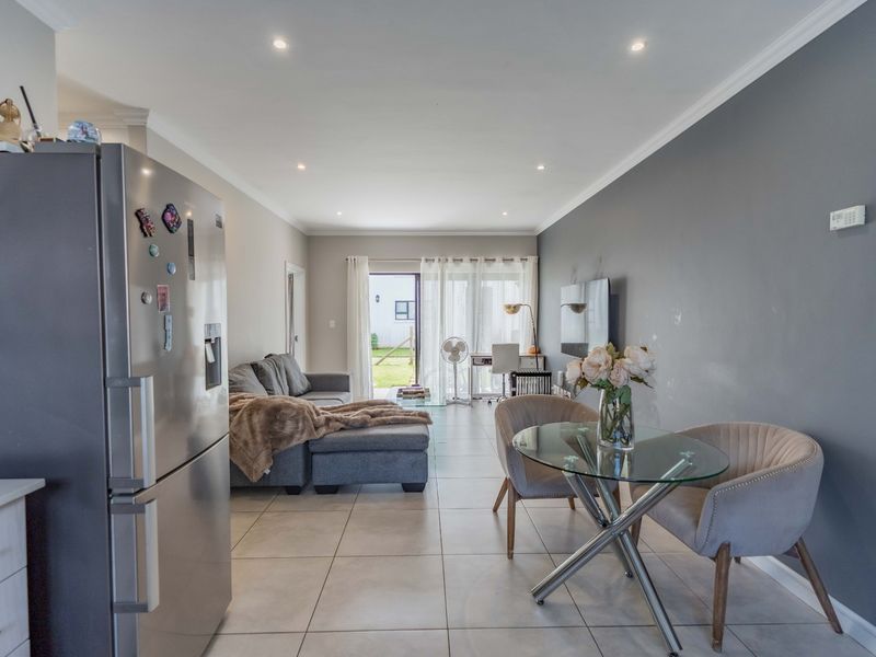 Open-plan living and dining area featuring tiled flooring, recessed lighting, and direct access to an outdoor space through a sliding glass door.