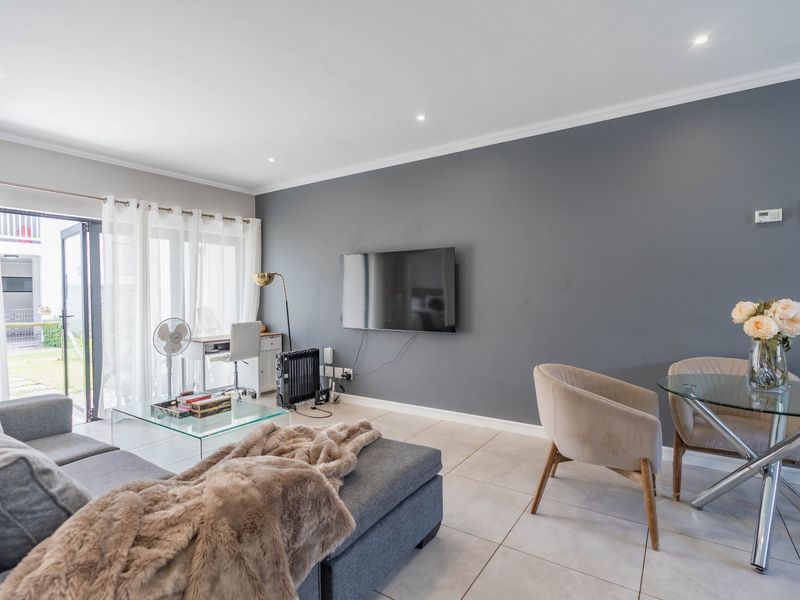 A bright living room featuring tiled flooring, recessed downlights, and a large sliding glass door providing access to the outdoor area.