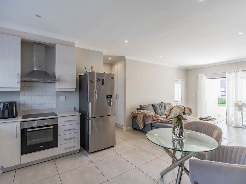 Modern open-plan living area featuring a well-equipped kitchen with built-in appliances, tiled flooring, and seamless access to an outdoor patio space.