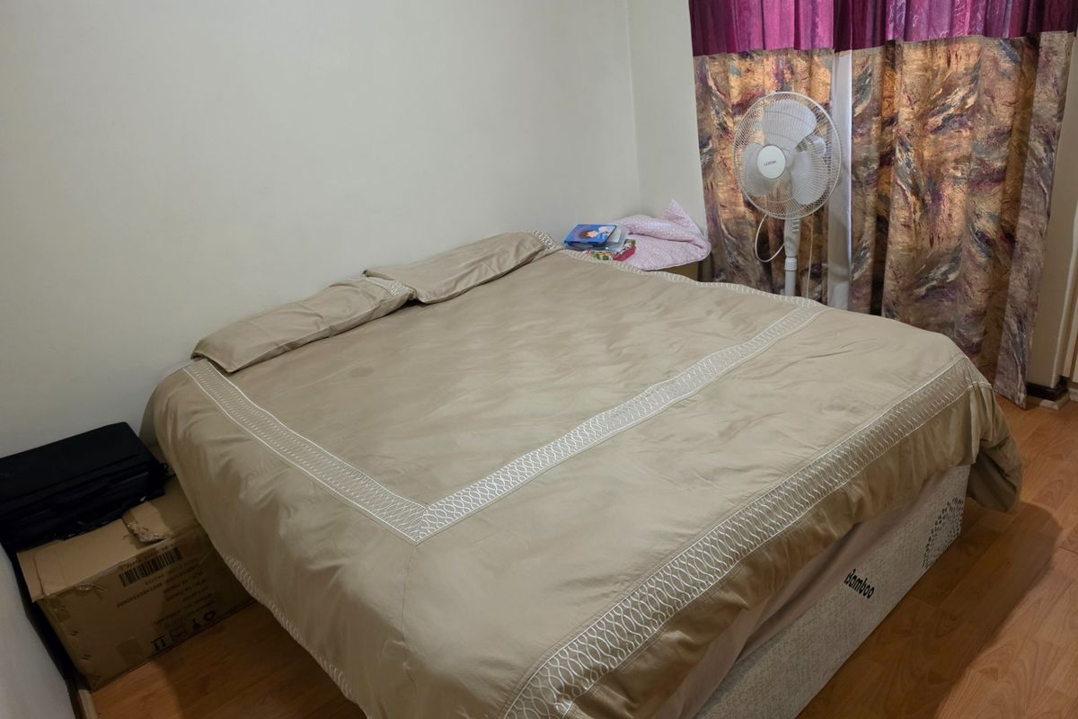 A functional bedroom featuring laminate flooring and neutral wall finishes, providing a blank canvas for potential interior design updates.