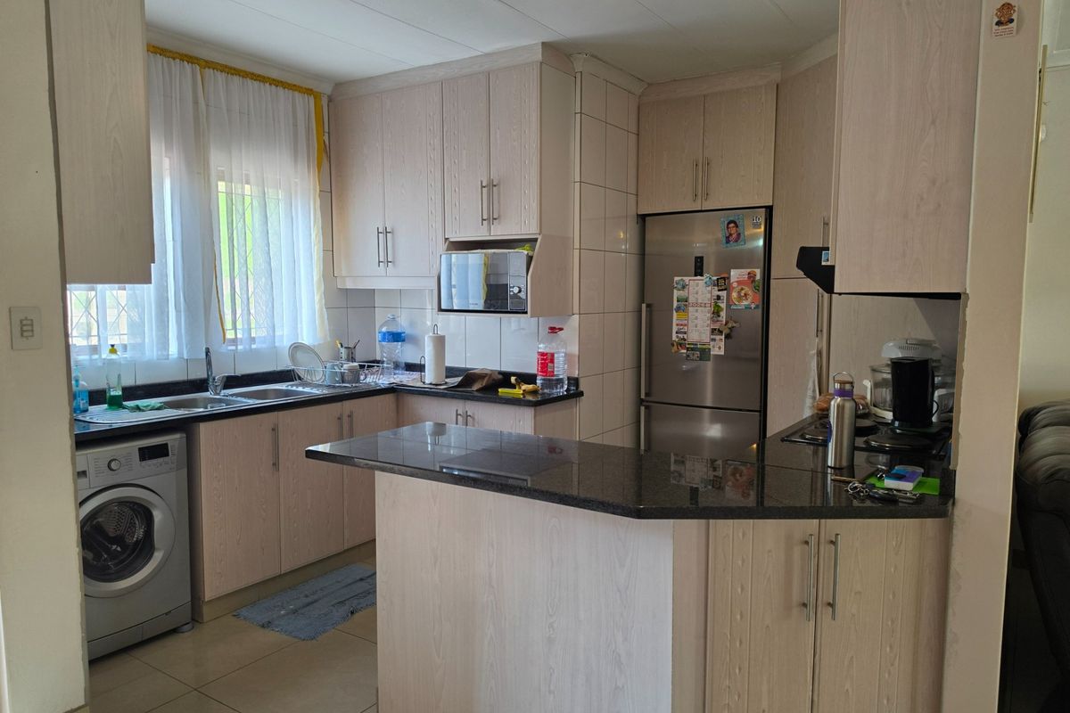 A functional kitchen featuring light wood-finish cabinetry, granite countertops, a tiled backsplash, and integrated appliance space, offering a practical layout for daily use.