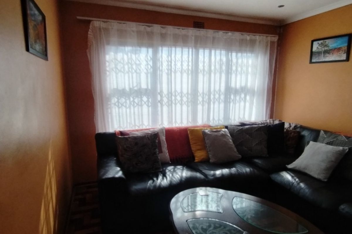 A cozy living room featuring classic parquet flooring, recessed downlighting, and a large window fitted with a security gate for added peace of mind.