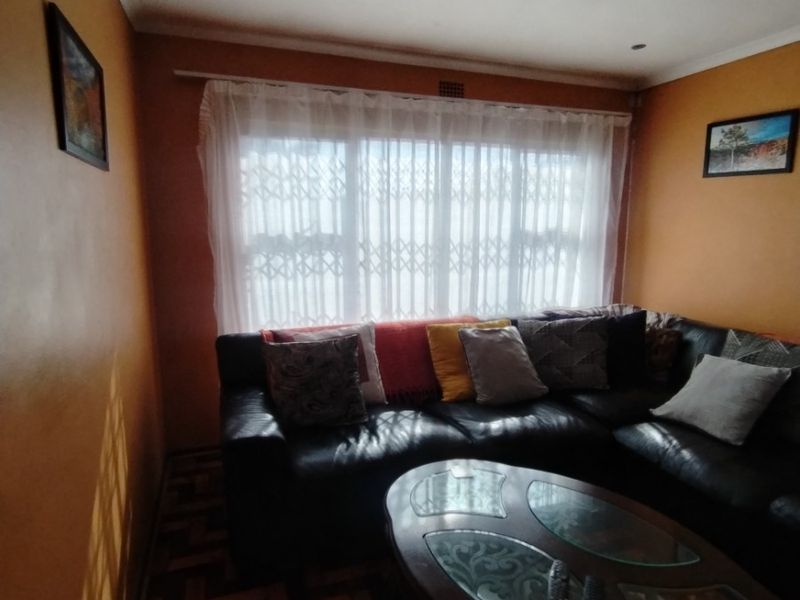 A cozy living room featuring classic parquet flooring, recessed downlighting, and a large window fitted with a security gate for added peace of mind.