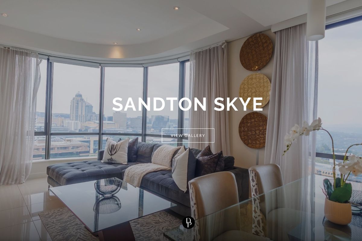 Modern living area featuring expansive floor-to-ceiling windows with panoramic city views, recessed lighting, and sleek tiled flooring.