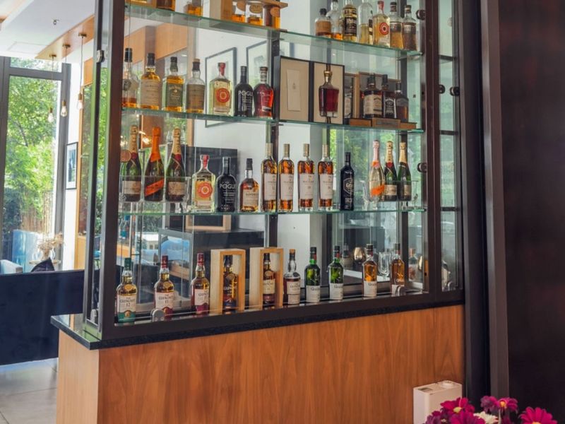 A sophisticated built-in bar area featuring custom glass display shelving, timber cabinetry, and a sleek stone countertop.