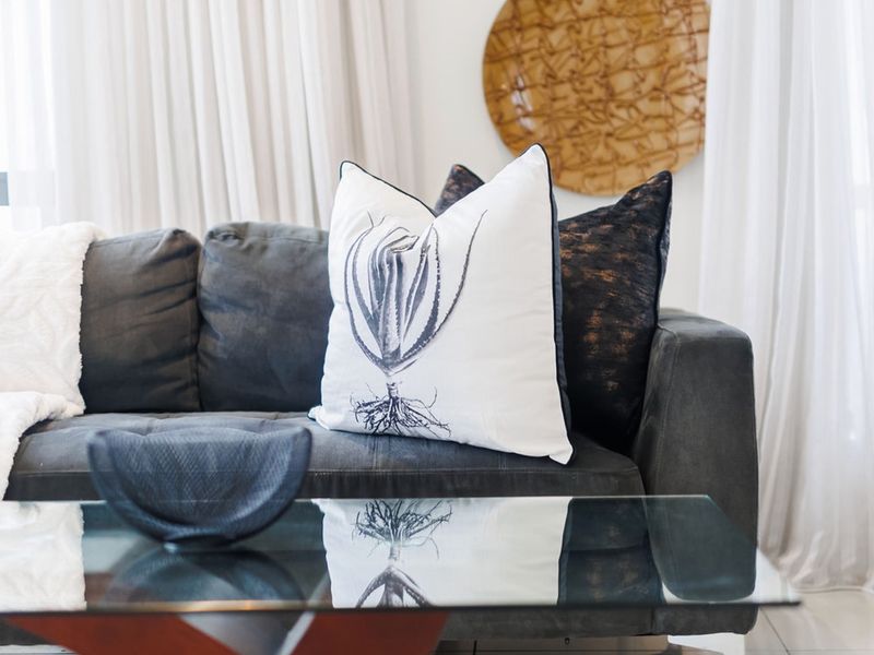 A close-up view of a living room seating area featuring neutral curtains and modern interior styling.