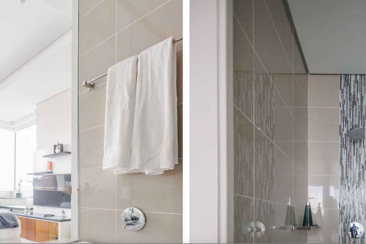 A modern bathroom featuring neutral wall tiles, a decorative mosaic tile accent in the shower area, and chrome fixtures.