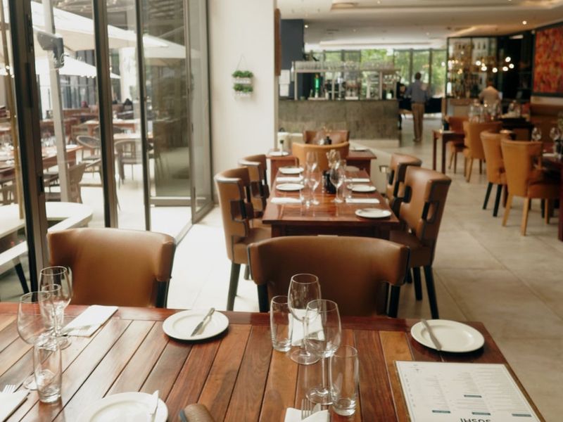 A spacious, well-lit dining area featuring large glass sliding doors opening to an outdoor patio, tiled flooring, and a built-in bar counter.
