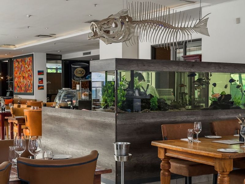 A dining area featuring a large built-in aquarium partition and recessed ceiling lighting, creating a distinct atmosphere for a restaurant or dining space.