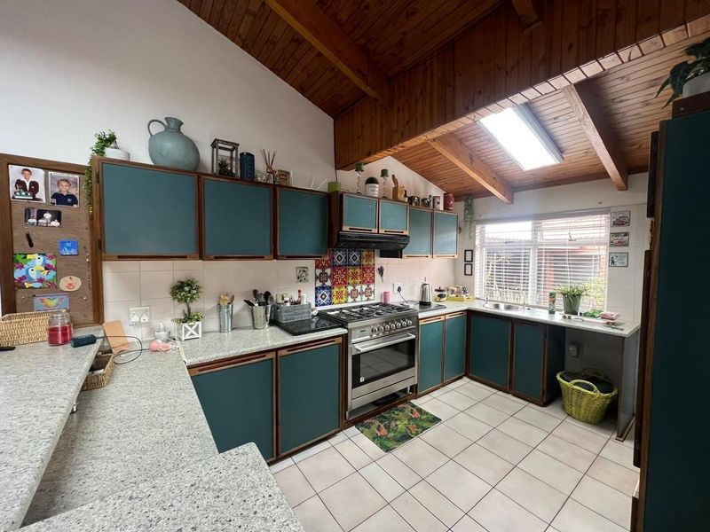 A functional kitchen featuring a gas cooktop, built-in oven, extractor fan, and a skylight set within an exposed timber beam ceiling.