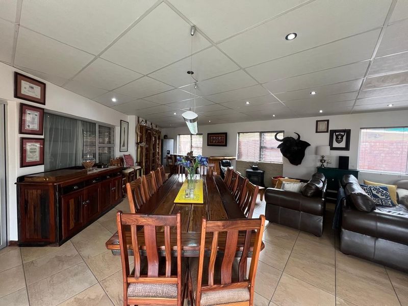 Spacious open-plan living and dining area featuring tiled flooring, recessed lighting, and a built-in bar counter, offering a versatile layout for entertaining.