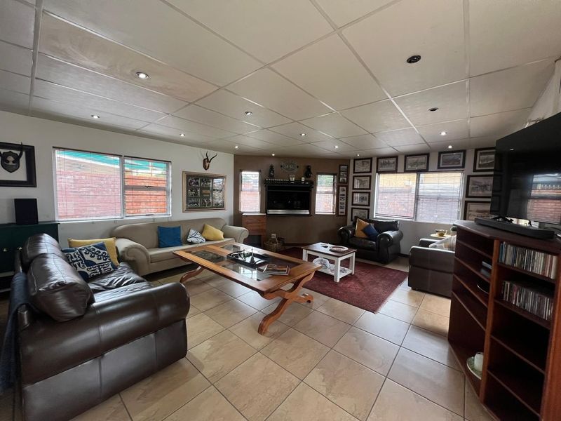 Spacious living room featuring tiled flooring, a built-in fireplace, and a drop ceiling with recessed lighting.