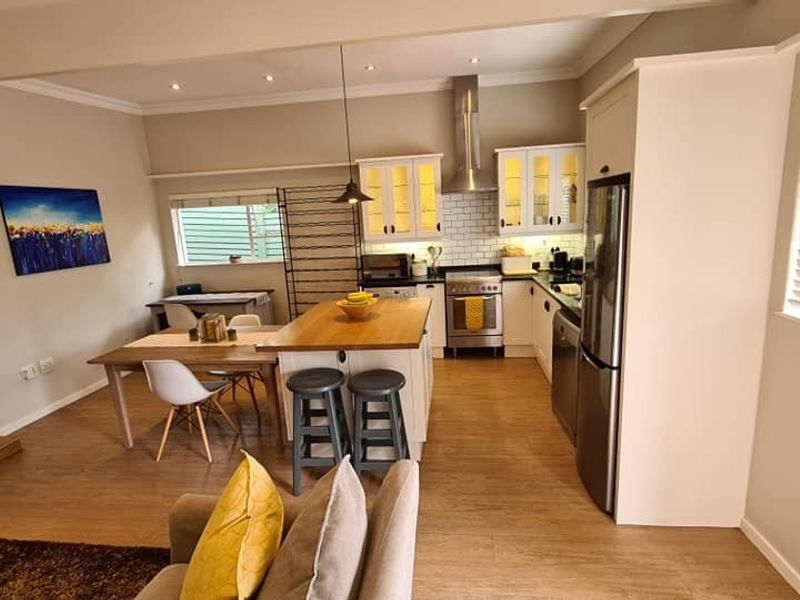 Open-plan kitchen and dining area featuring a central island, stainless steel appliances, subway tile backsplash, and warm timber-look flooring.