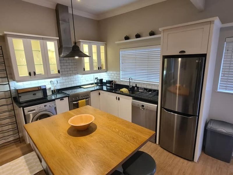 A well-appointed kitchen featuring white cabinetry, subway tile backsplash, stainless steel appliances, and a central wooden island with integrated storage and workspace.