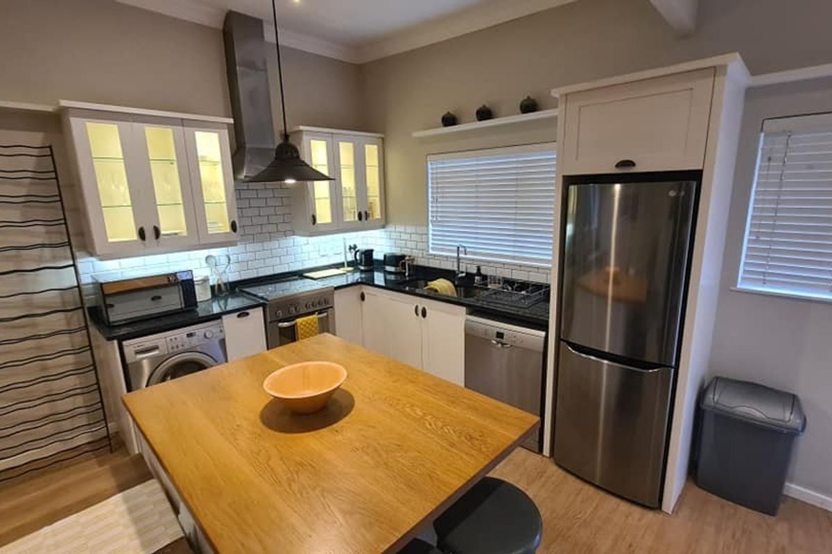 A well-appointed kitchen featuring white cabinetry, subway tile backsplash, stainless steel appliances, and a central wooden island with integrated storage and workspace.