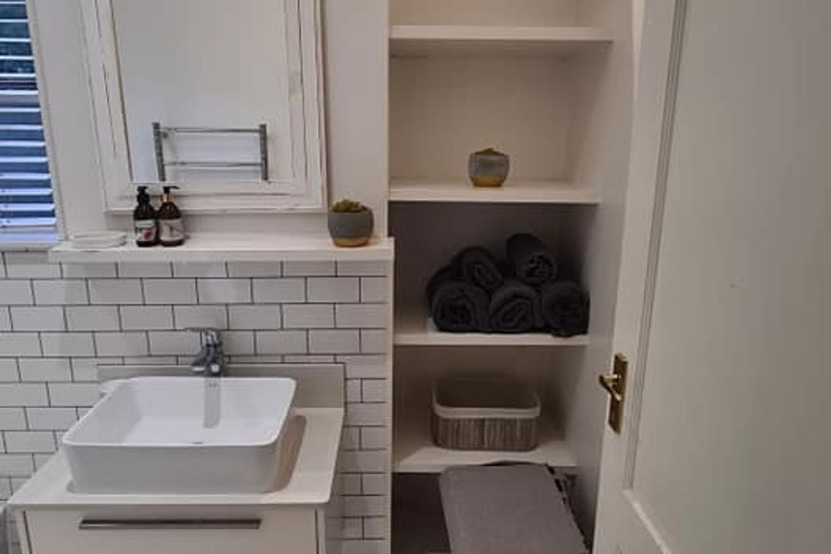 A modern bathroom featuring a vessel sink on a wall-mounted vanity, subway tile backsplash, and convenient built-in shelving for storage.