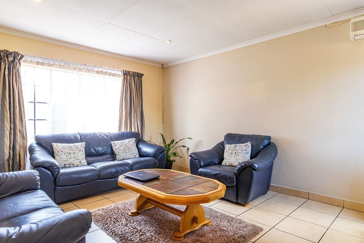 A comfortable living room featuring tiled flooring, a wall-mounted air conditioning unit, and recessed ceiling lighting.