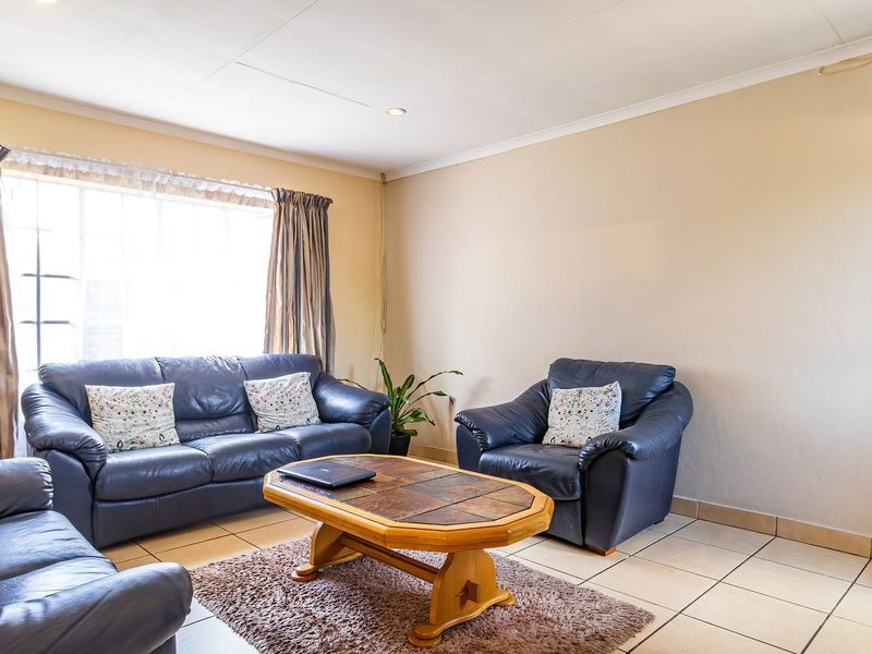 A comfortable living room featuring tiled flooring, a wall-mounted air conditioning unit, and recessed ceiling lighting.