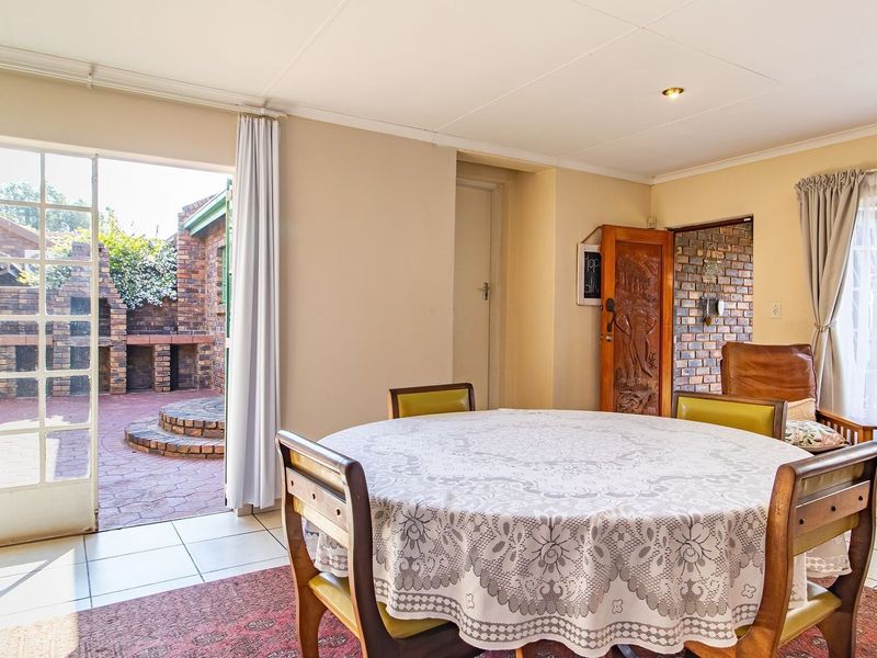 Dining area featuring tiled flooring and direct access to an outdoor patio through glass french doors, with exposed brick accents in the adjacent space.