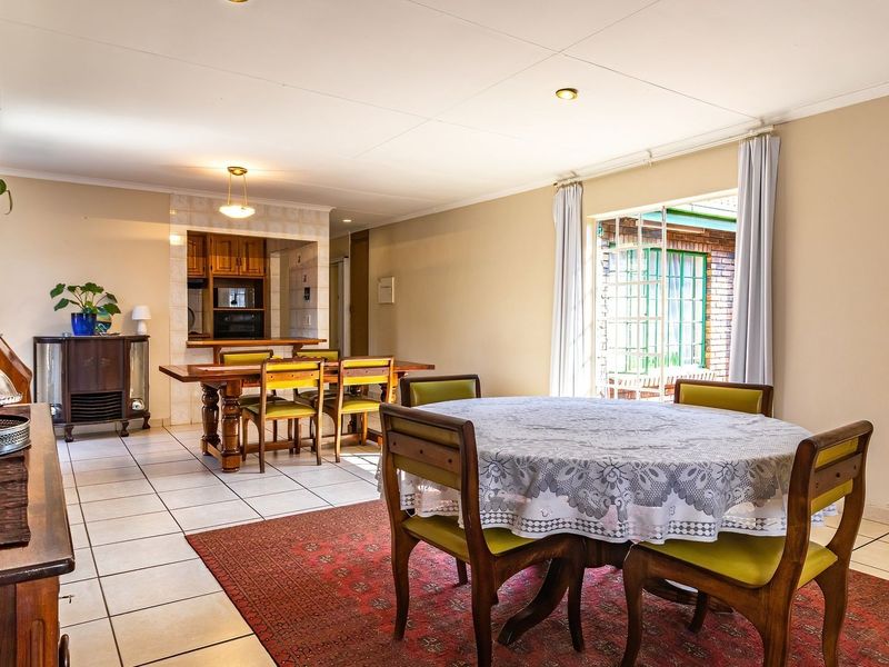 Spacious open-plan living and dining area featuring tiled flooring, a breakfast counter, and direct access to the exterior through a sliding glass door.