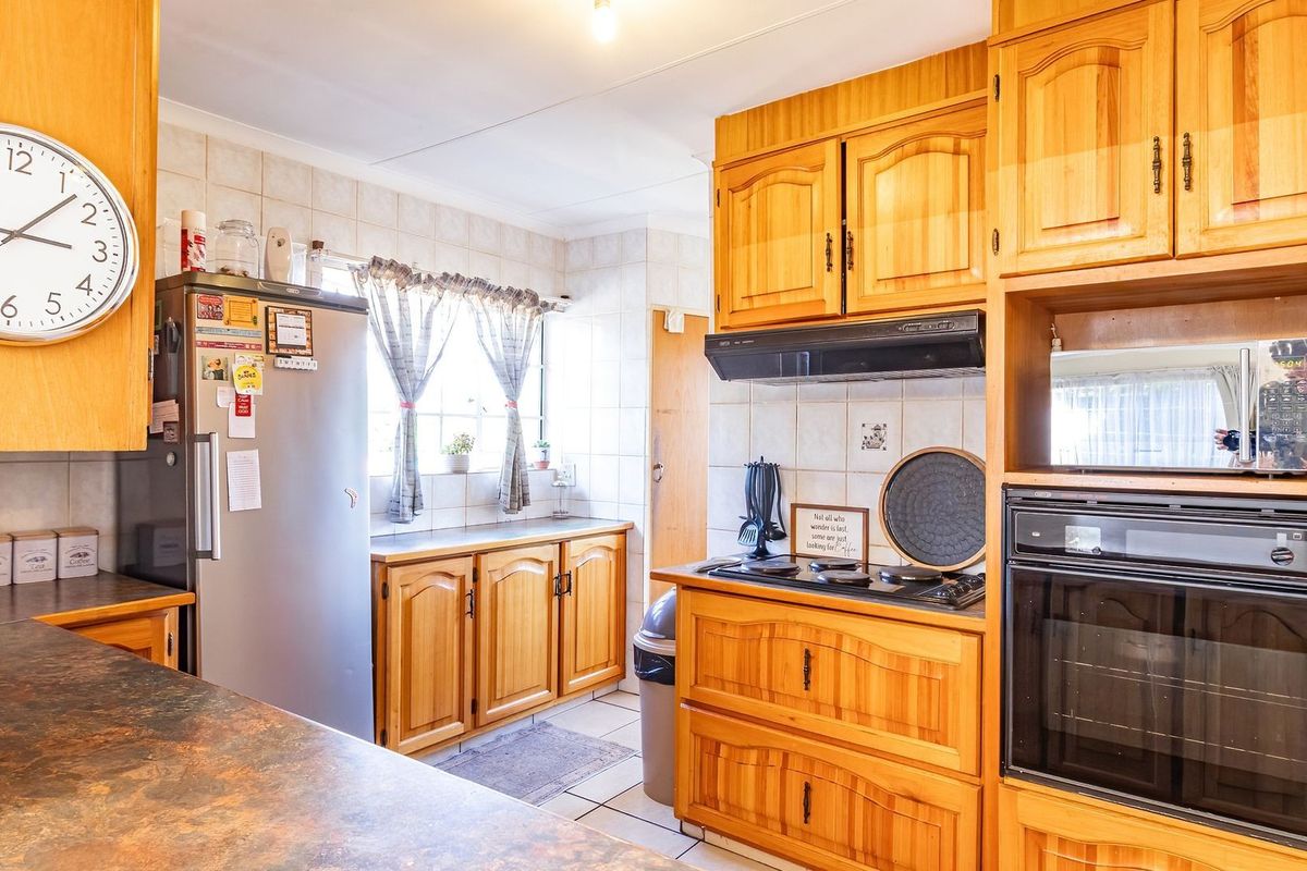 A functional kitchen featuring traditional wooden cabinetry, laminate countertops, a built-in oven, and a tiled backsplash, offering a classic aesthetic with practical storage.