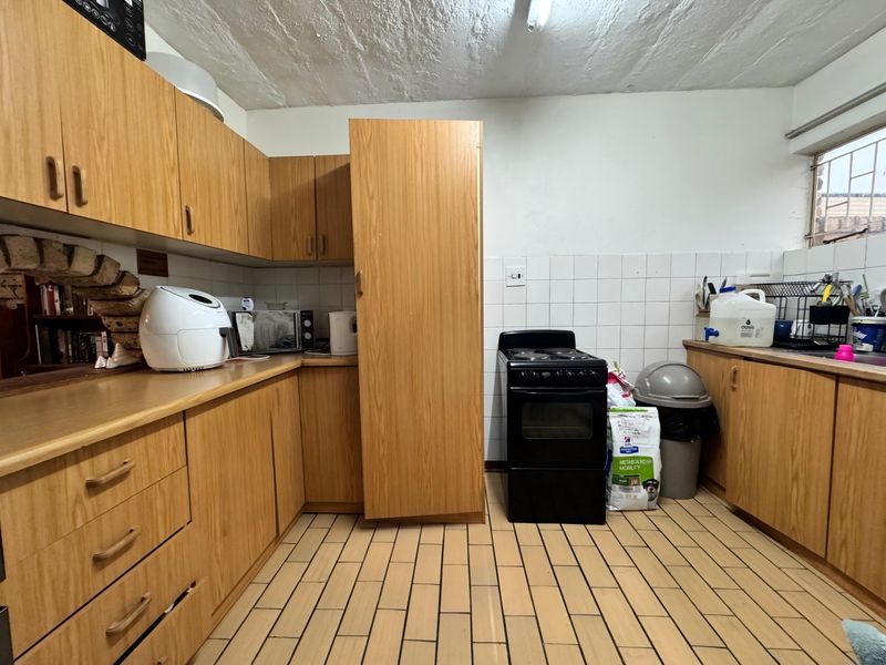 A functional kitchen featuring wood-look cabinetry, tiled flooring, and a tiled backsplash, offering a dated aesthetic with potential for modern renovation.