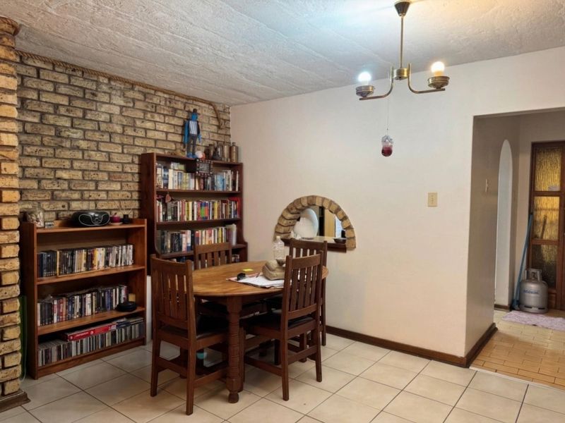 Dining area featuring an exposed brick wall, decorative archway, and tiled flooring, offering a rustic aesthetic with potential for modern updates.