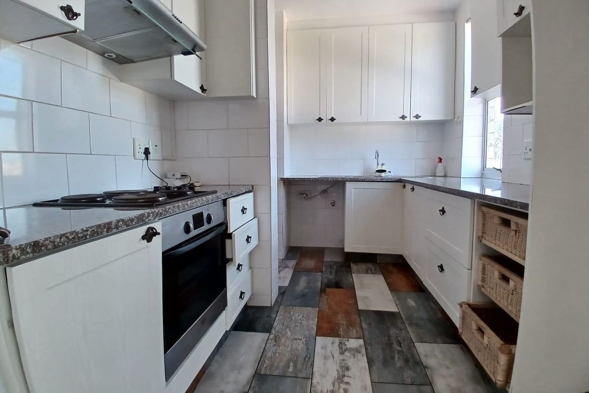 A functional kitchen featuring white cabinetry, granite countertops, subway tile backsplash, and integrated appliances with a distinctive multi-toned tiled floor.