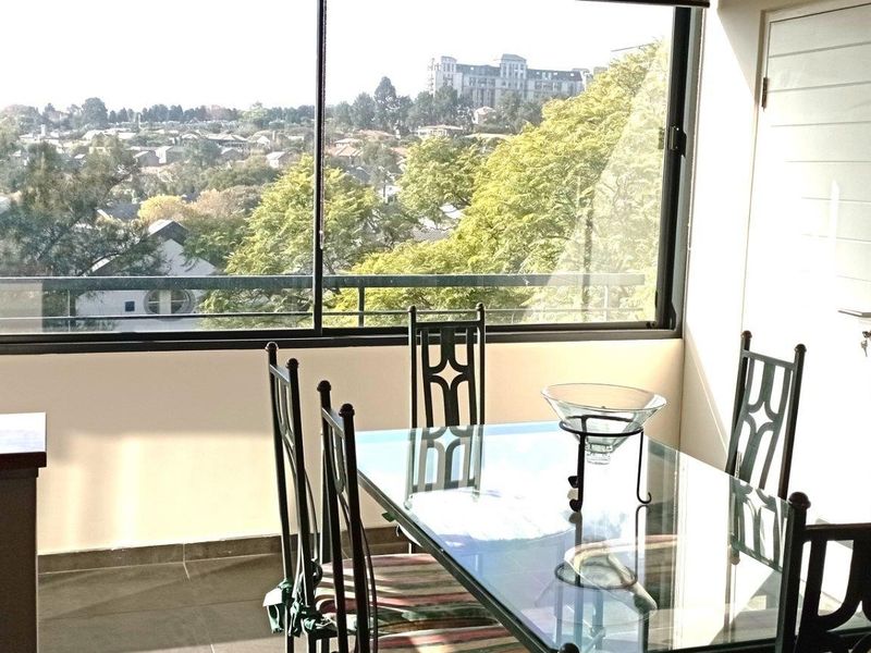A bright dining area featuring large windows with expansive neighbourhood views and tiled flooring.