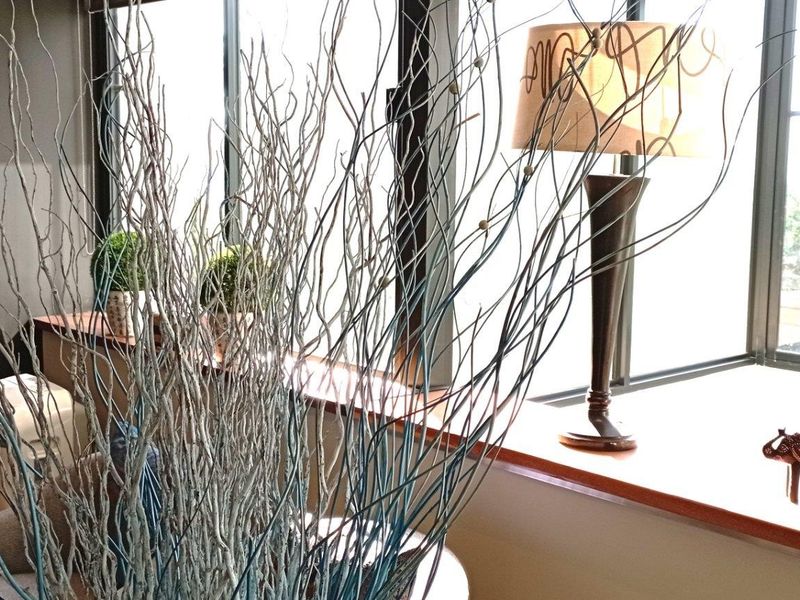 A living area featuring large windows with a wooden sill, providing natural light and a view.