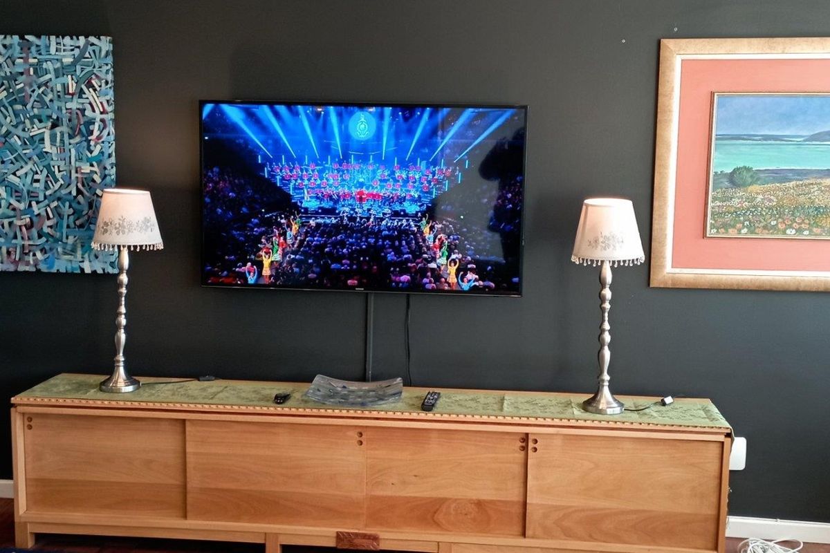 A living room featuring a dark accent wall with a mounted television and hardwood flooring.