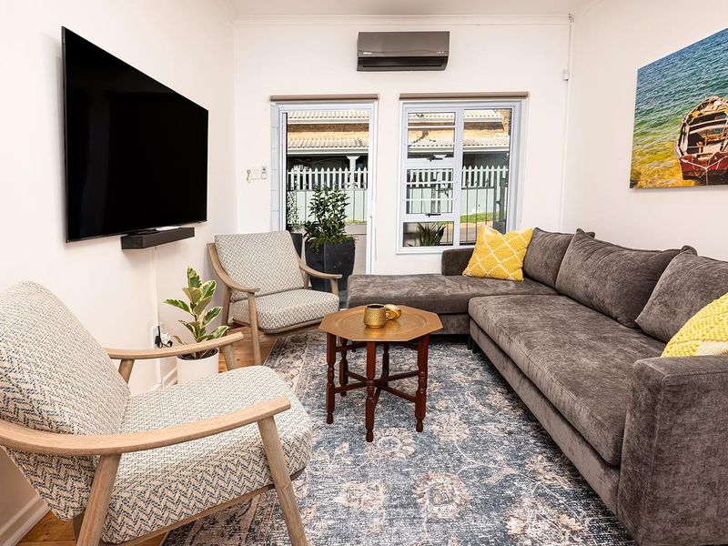 A comfortable living room featuring a wall-mounted air conditioning unit, neutral walls, and access to an outdoor area through sliding doors.