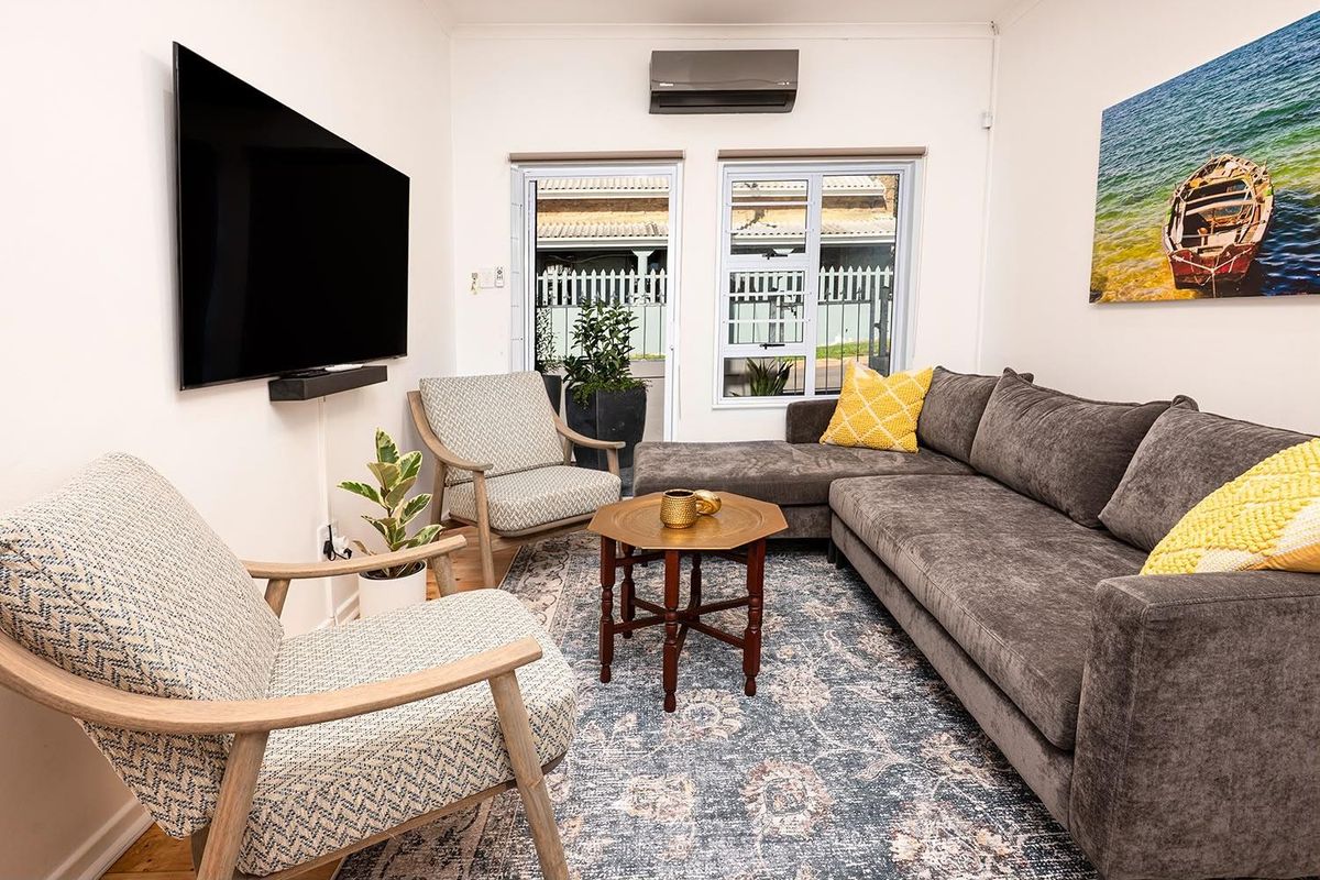 A comfortable living room featuring a wall-mounted air conditioning unit, neutral walls, and access to an outdoor area through sliding doors.