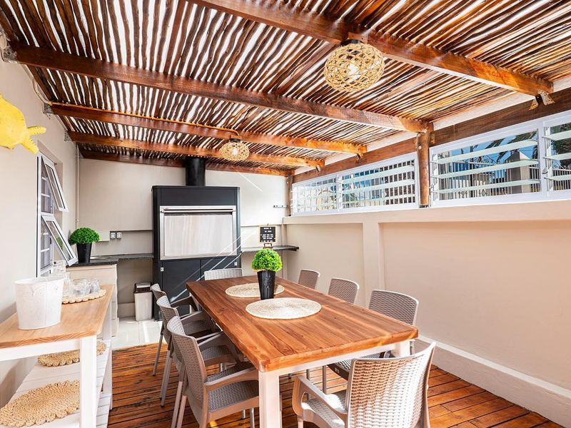Covered patio area featuring a built-in braai, timber slat ceiling, and wooden decking, providing an ideal space for outdoor dining and entertainment.