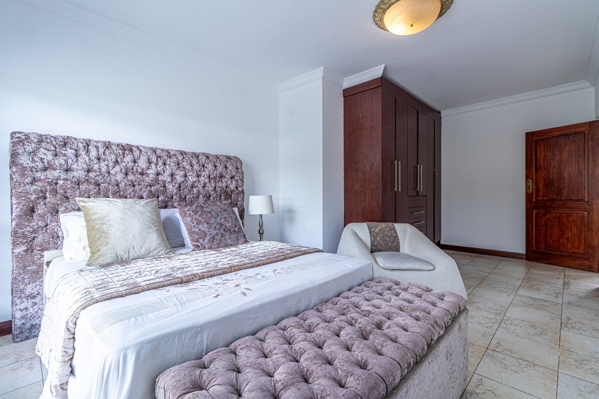 A well-maintained bedroom featuring tiled flooring, a built-in wooden wardrobe, and coved ceiling detailing.