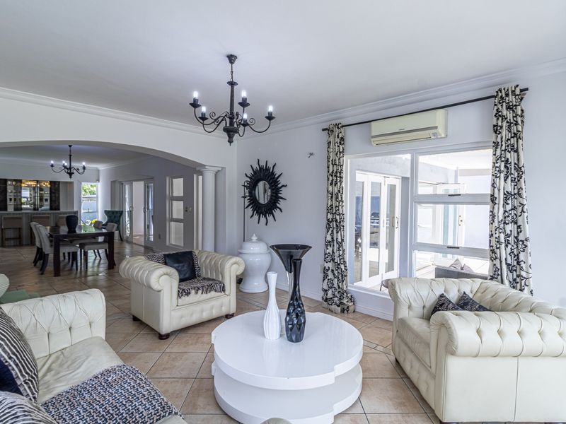 Spacious open-plan living and dining area featuring ceramic tile flooring, arched architectural details, and direct access to the outdoor patio through sliding glass doors.