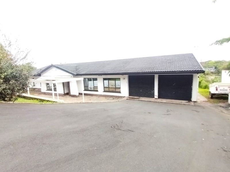 Front exterior view of a single-story house featuring a double garage, tiled roof, and a paved driveway leading to the entrance.