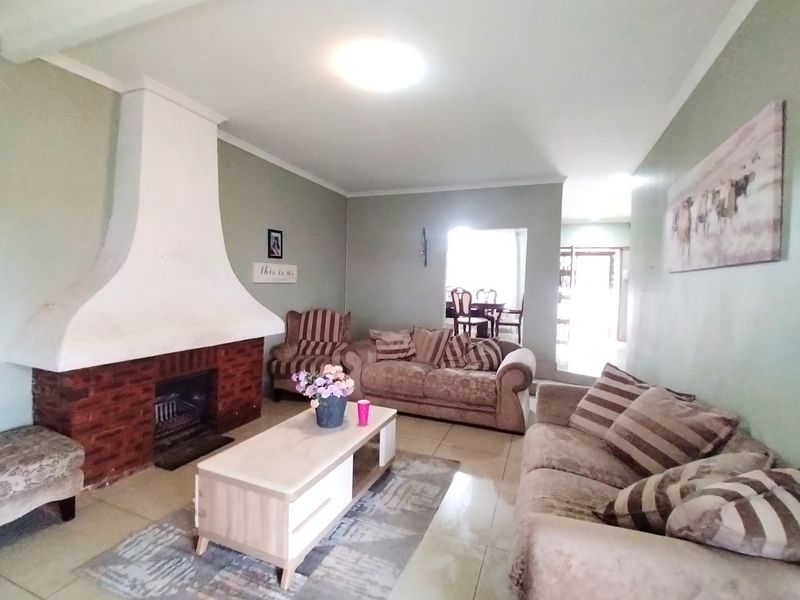 Spacious living room featuring a prominent brick fireplace and neutral tiled flooring, offering a comfortable and inviting atmosphere.