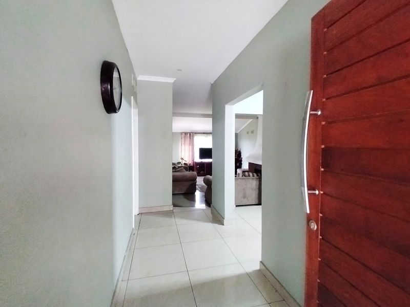 A bright entrance hall featuring tiled flooring and a solid wood front door, leading into the main living area of the home.