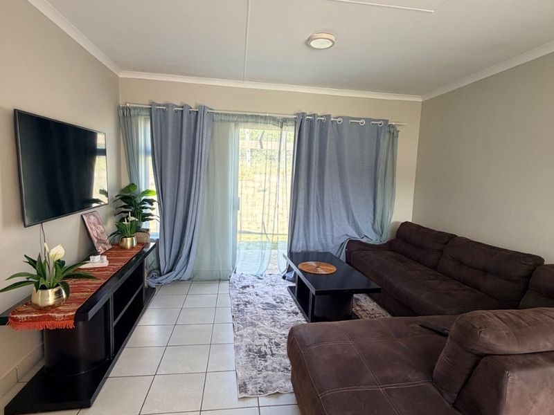 A living room featuring tiled flooring and a sliding glass door providing access to the exterior.