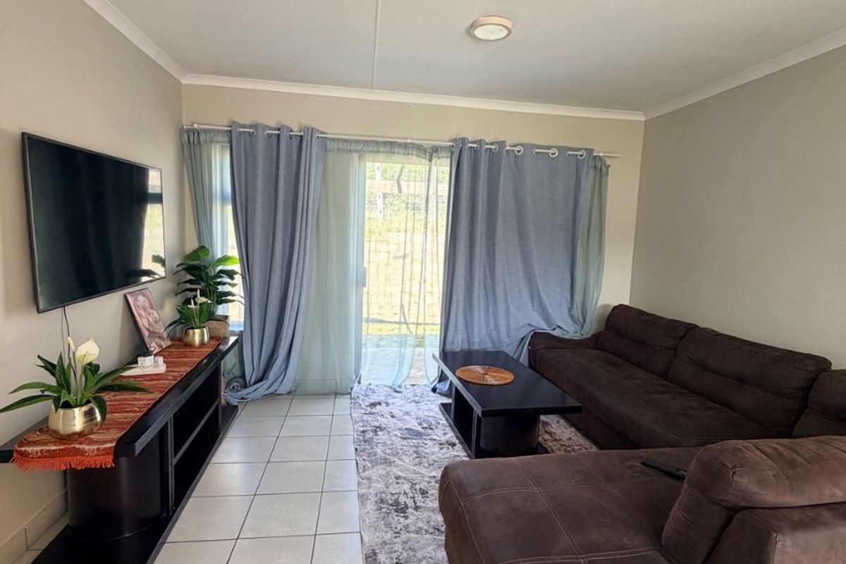 A living room featuring tiled flooring and a sliding glass door providing access to the exterior.