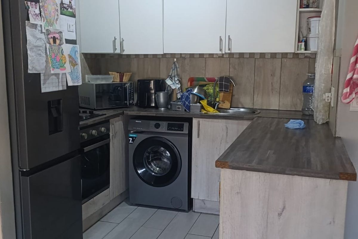 Compact kitchen featuring modern wood-look cabinetry, laminate countertops, integrated oven and hob, and a tiled backsplash, providing a functional workspace.