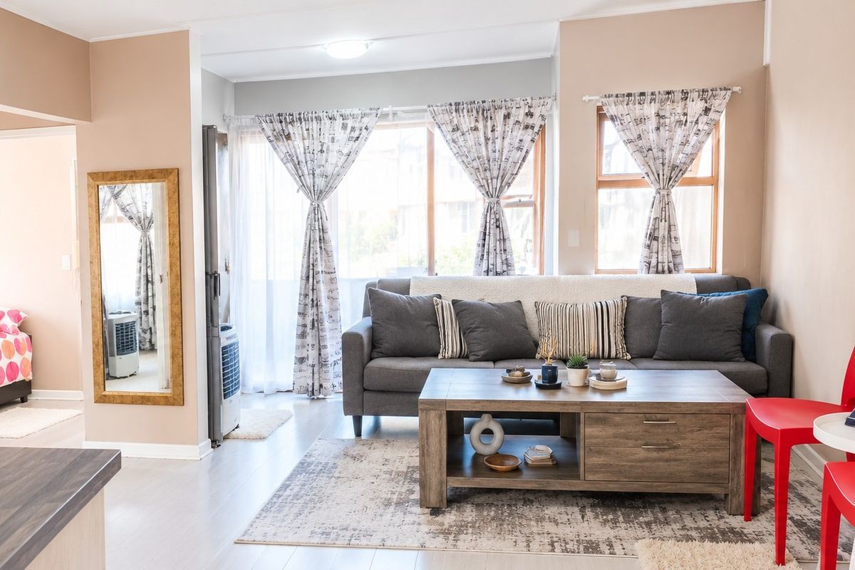 A bright and well-maintained living room featuring laminate flooring and large windows that provide ample natural light.